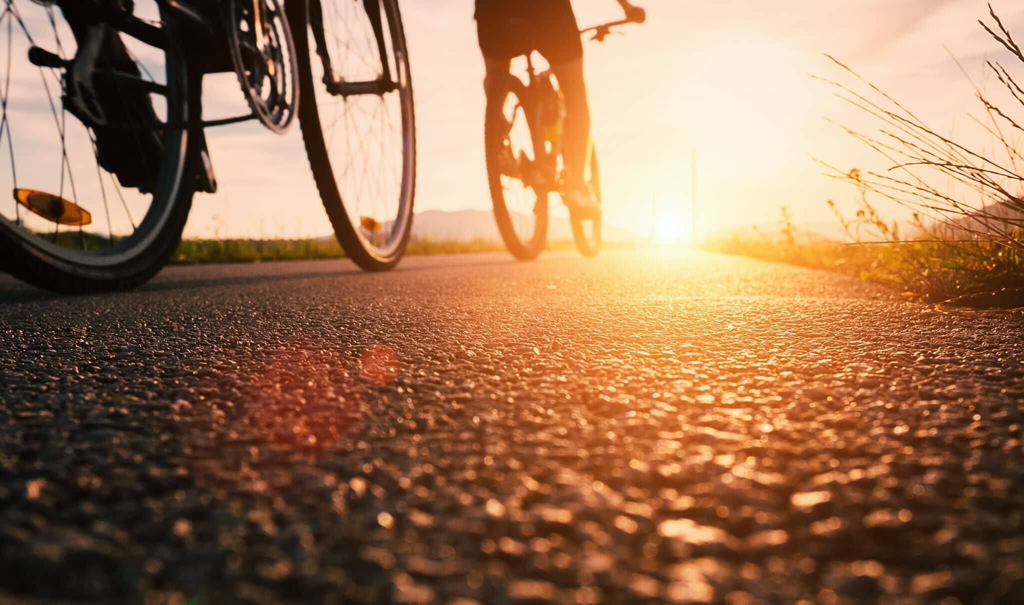A road with a bicycle in the foreground and a person riding a bicycle in the background.