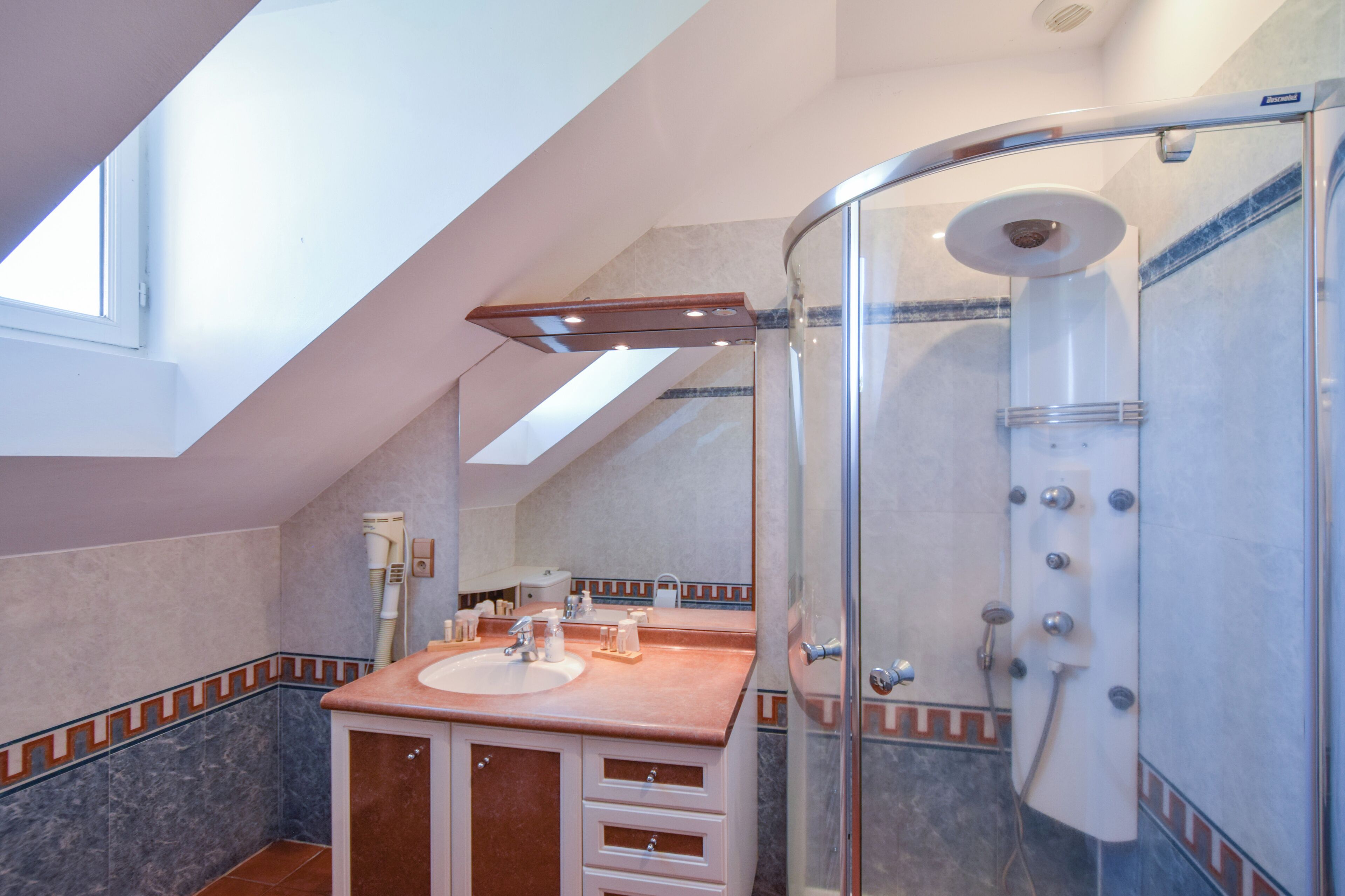 Un baño moderno con ducha de vidrio, tocador con lavamanos y un espejo grande.