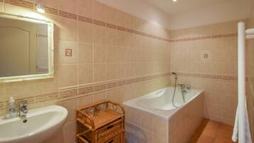 A bathroom with a sink, a mirror, a bathtub, and a shower.