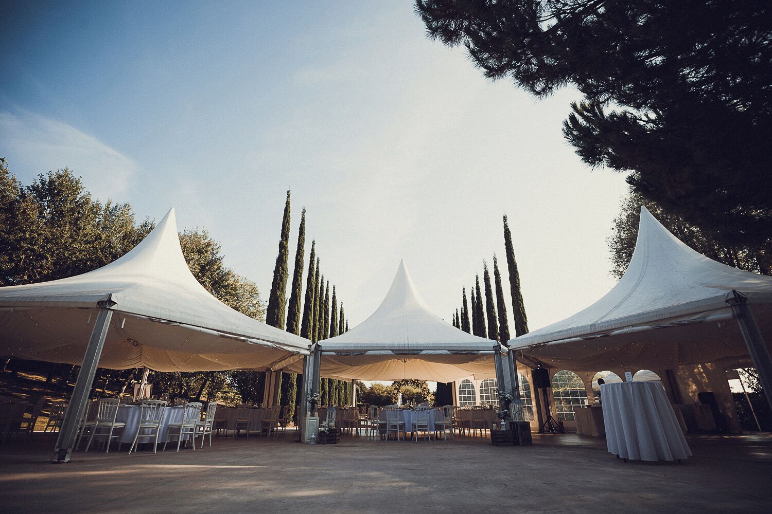 A tented outdoor event space with tables and chairs arranged for guests.