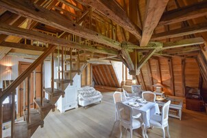 Un interior rústico de madera con un dormitorio en entrepiso, un comedor y una escalera.