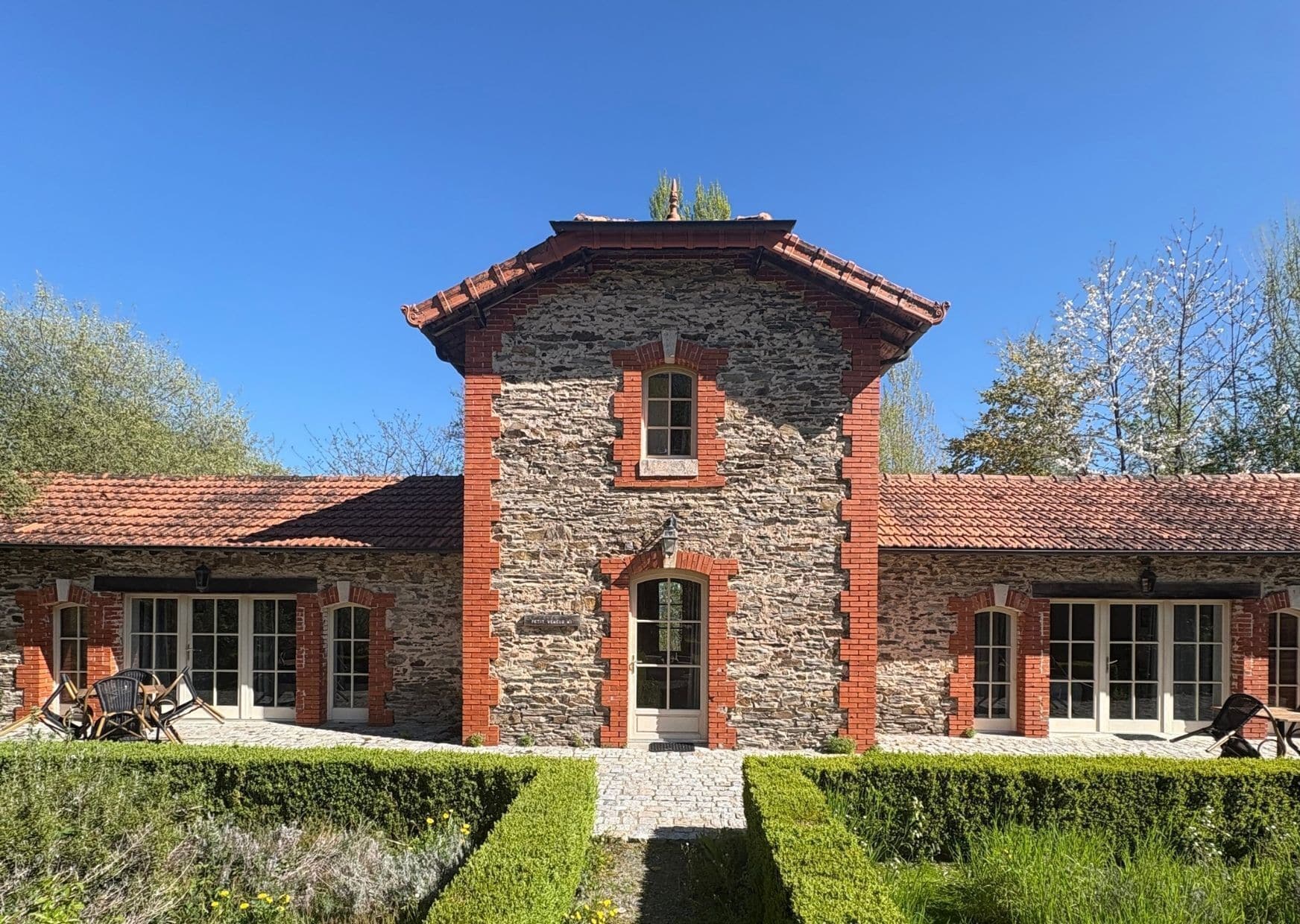 A stone and brick building with a central tower, large windows, and a paved entrance.