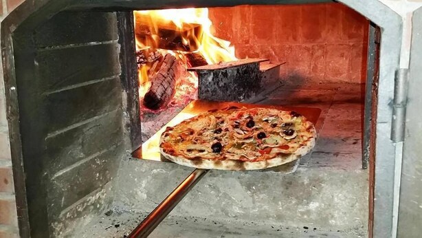 A pizza being baked in a wood-fired oven. - Hotel Marrakech Residence (Marrakech)