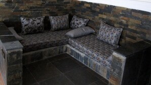 Un rincón con asientos, pared de piedra y ventilador de techo.