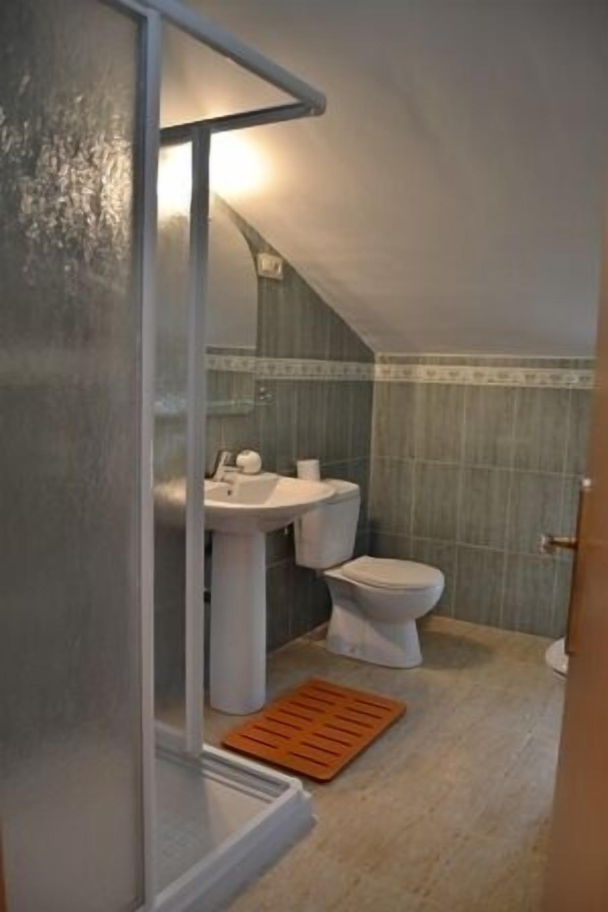 Un baño pequeño y estrecho con inodoro, lavabo y zona de ducha.