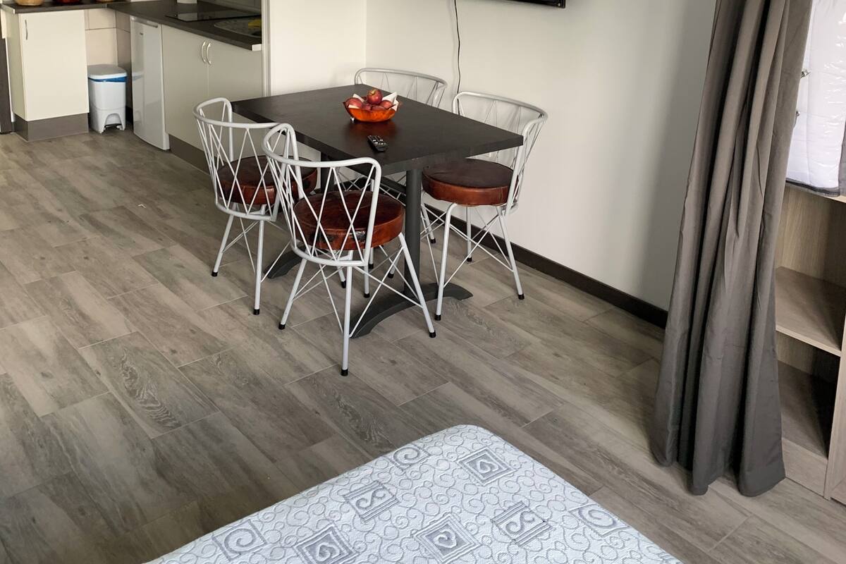 Une cuisine moderne avec des meubles blancs, un four à micro-ondes et un coin repas comprenant une table et des chaises.