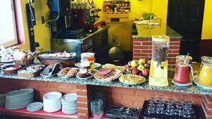 A breakfast bar with various food items, a coffee machine, and a clock on the wall. - Spa Rural Mirador de Miranda (Belmonte de Miranda)