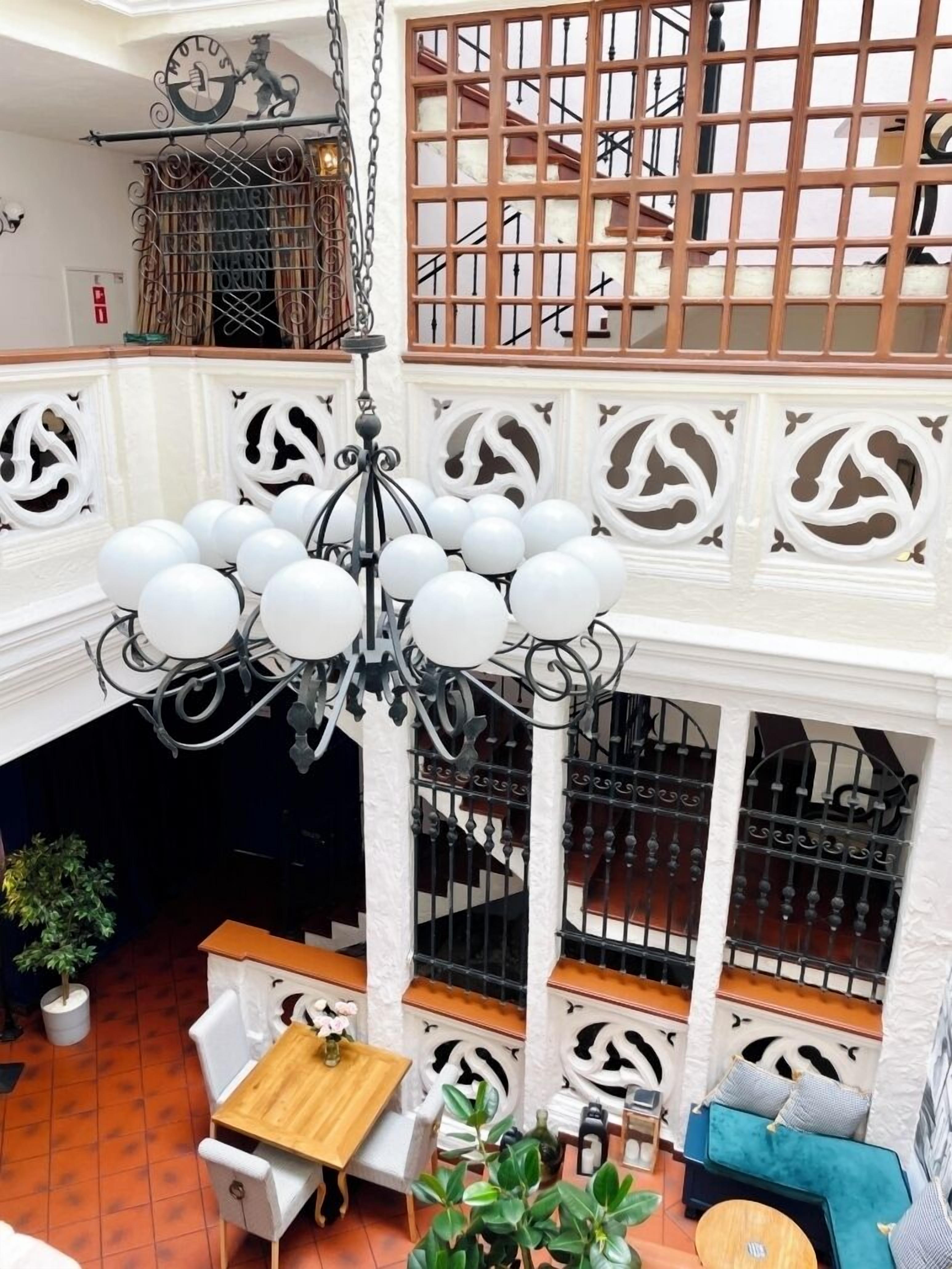 A multi-level interior with a chandelier, white decorative moldings, a staircase, and seating areas.
