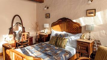 A traditional bedroom with a wooden bed, a nightstand with a lamp, a dresser, and a mirror.