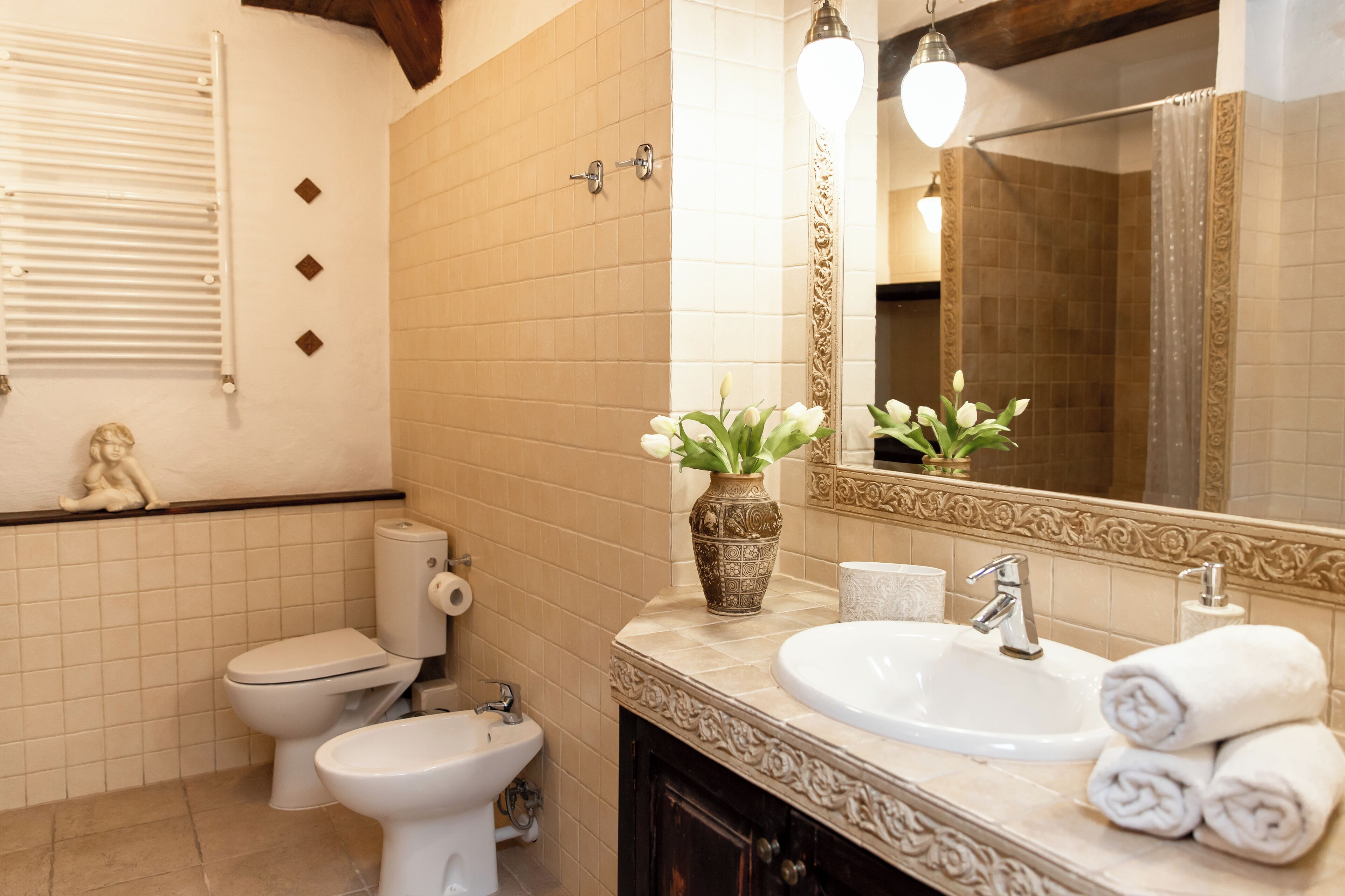 A bathroom with a toilet, bidet, sink, and a decorative mirror.