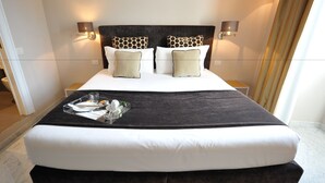 A large bed with a dark headboard, white bedding, and two wall-mounted lamps. - Angel Spagna Suite (Rome)