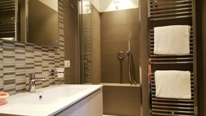 Bathroom features a large mirror, sink, and glass-enclosed shower with handheld showerhead.
