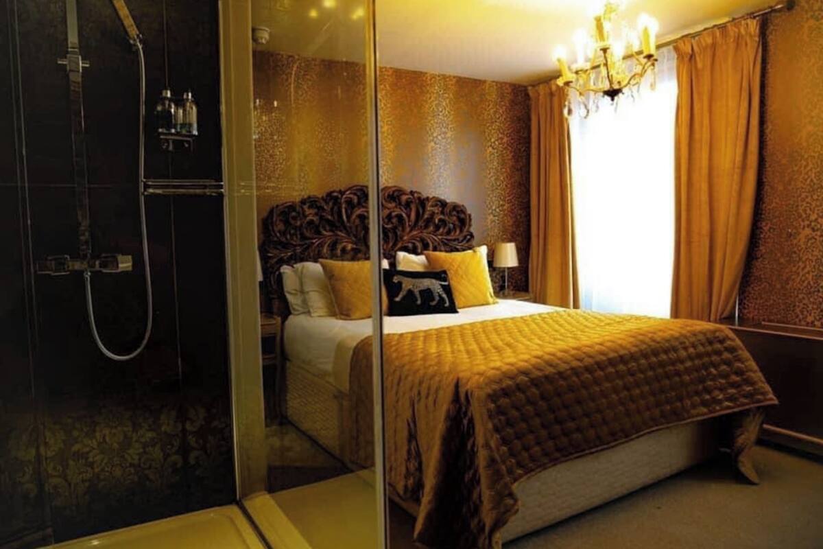 A hotel room with a large bed, a shower area, and a chandelier.