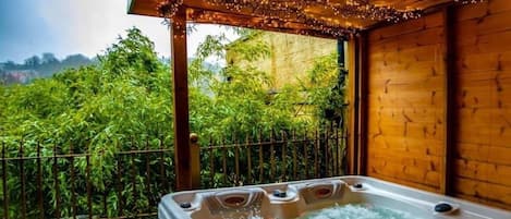 A hot tub with multiple jets, surrounded by a wooden structure and bamboo plants.