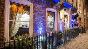 A brick building with large windows, a metal fence, and a small garden area. - OYO The Townhouse (Durham)