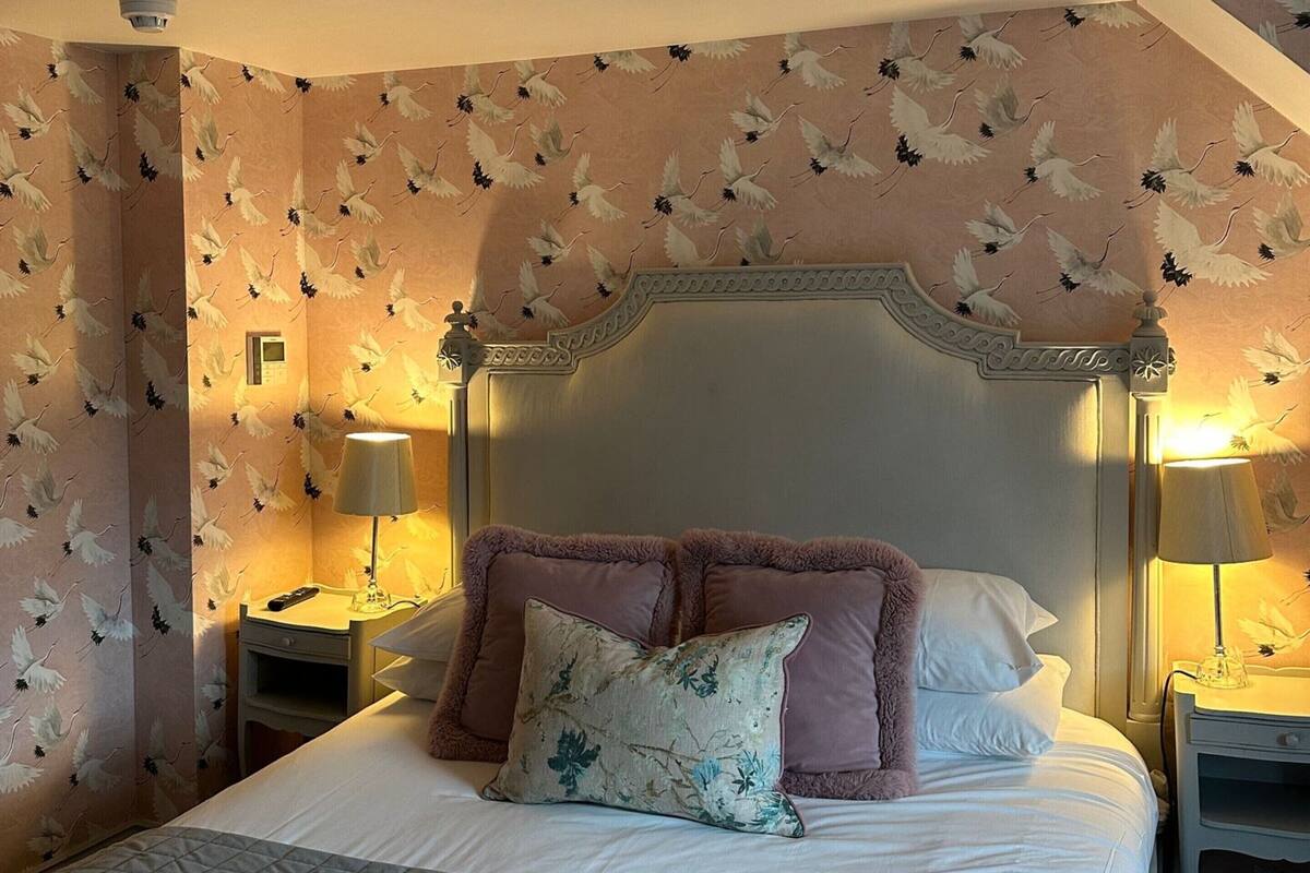 A hotel room with a large bed, two bedside tables, and a headboard with a decorative design.