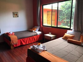 Habitación de hotel con dos camas, una mesita y ventana con vistas a zonas verdes.