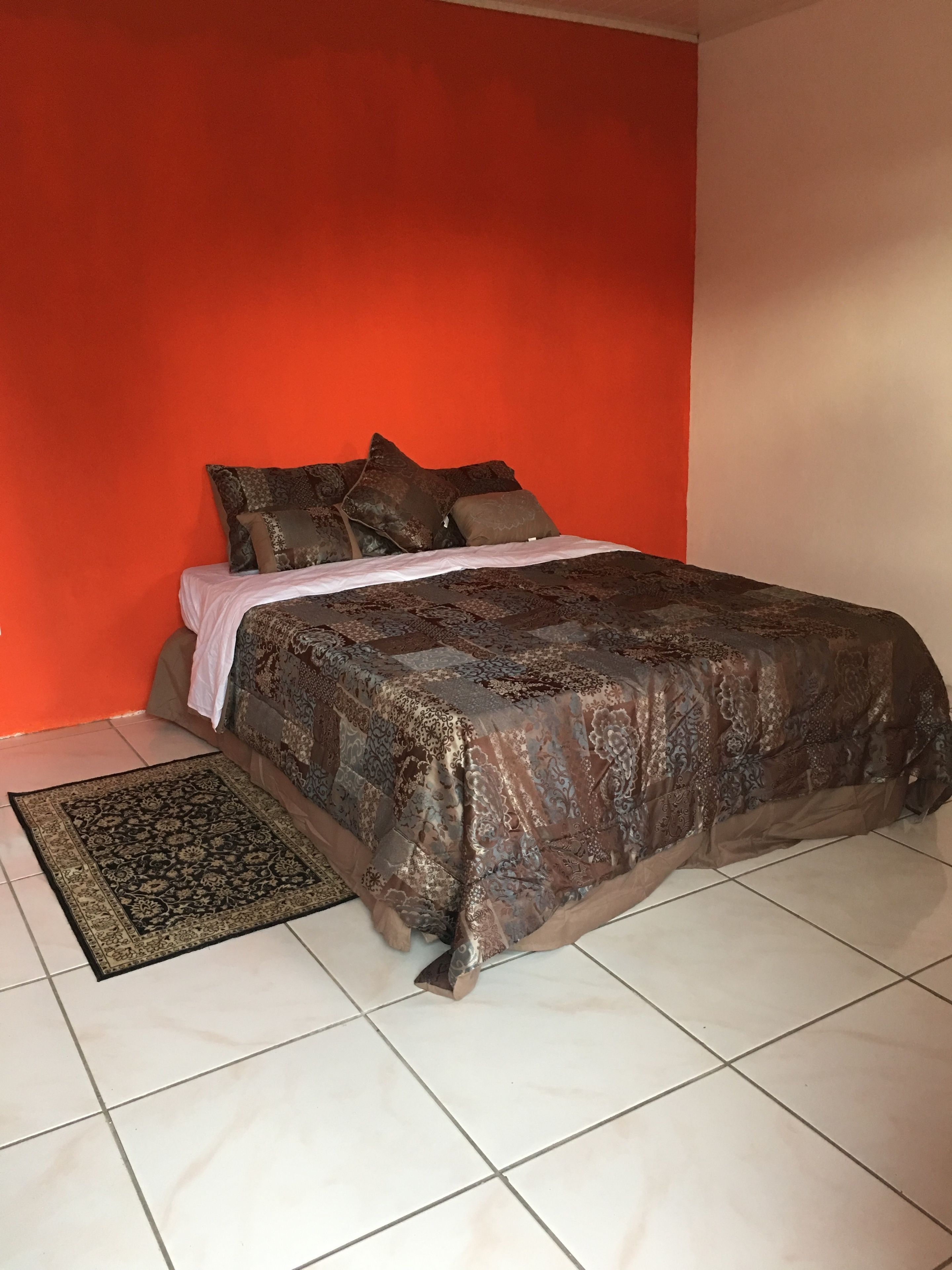 Un dormitorio con cama, almohadas y alfombra.