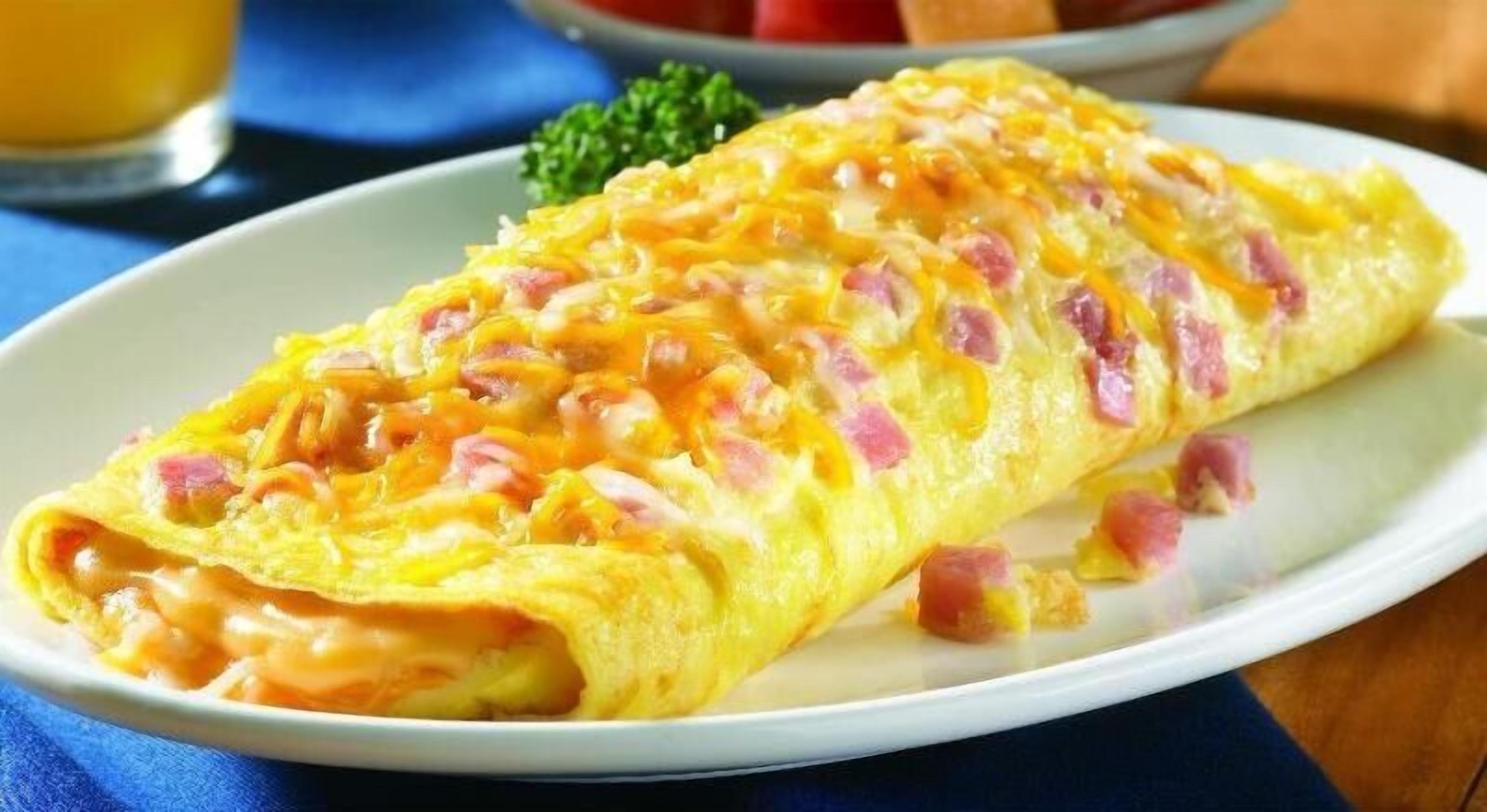 Omelet estilitzada amb formatge i pernil sobre un plat.