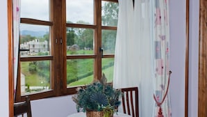 Une pièce avec une grande fenêtre, une table sur laquelle se trouve un panier de fleurs et une chaise.