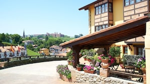 Un bâtiment doté d’un balcon, de plantes en pot et offrant une vue sur une colline surmontée d’un château.