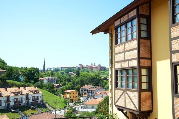 A residential area with traditional architecture, including a building with a wooden facade and a view of a distant castle.