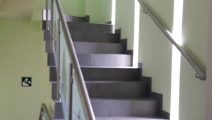 Una escalera con barandales de metal y pasamanos, que conduce a un piso superior.
