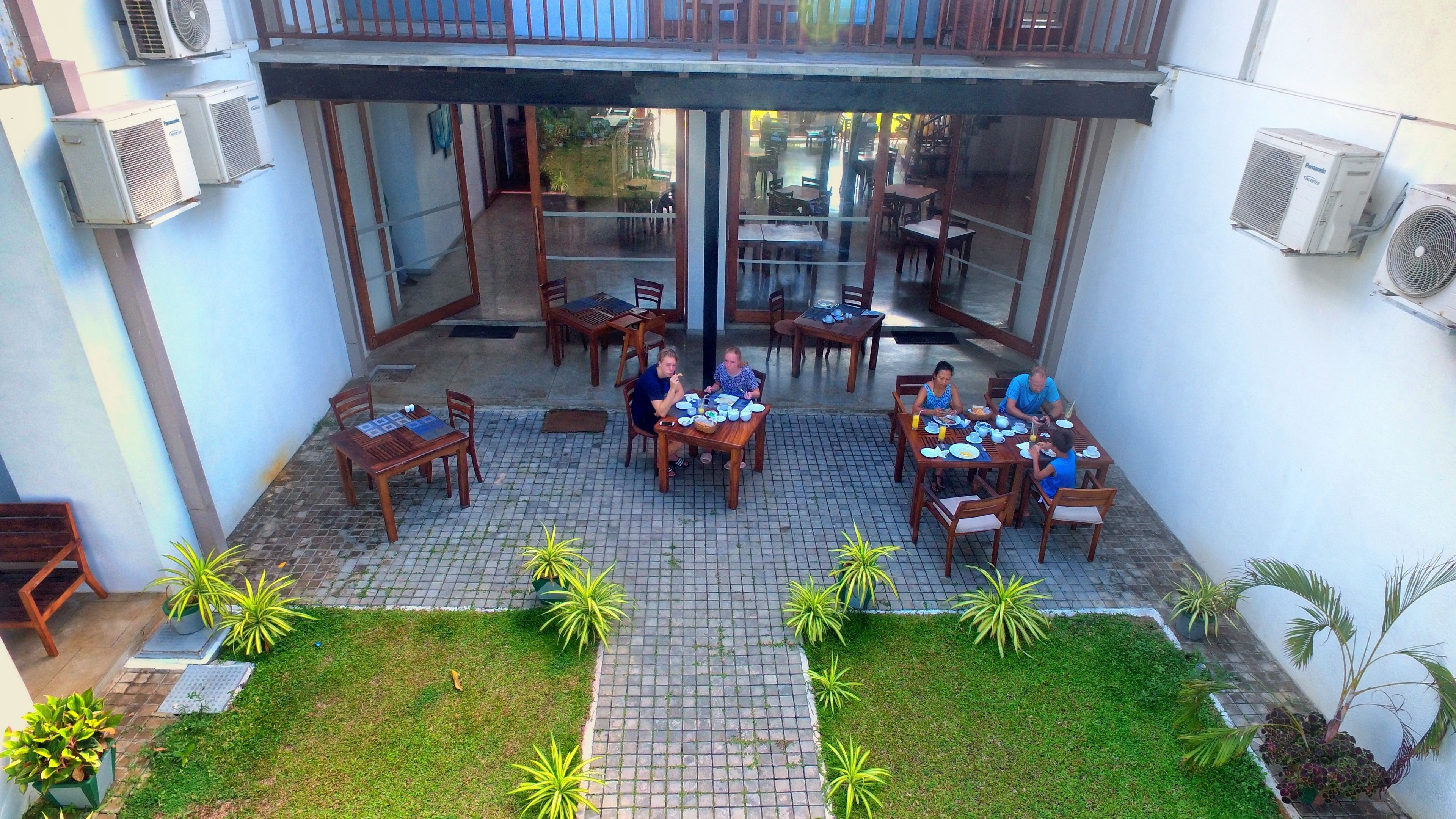A courtyard with outdoor seating, air conditioning units, and potted plants.