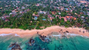Vista aérea de una zona residencial costera con casas, una playa y aguas turquesas cristalinas.