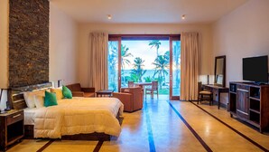 Habitación de hotel con cama, escritorio, televisión y vista a palmeras.