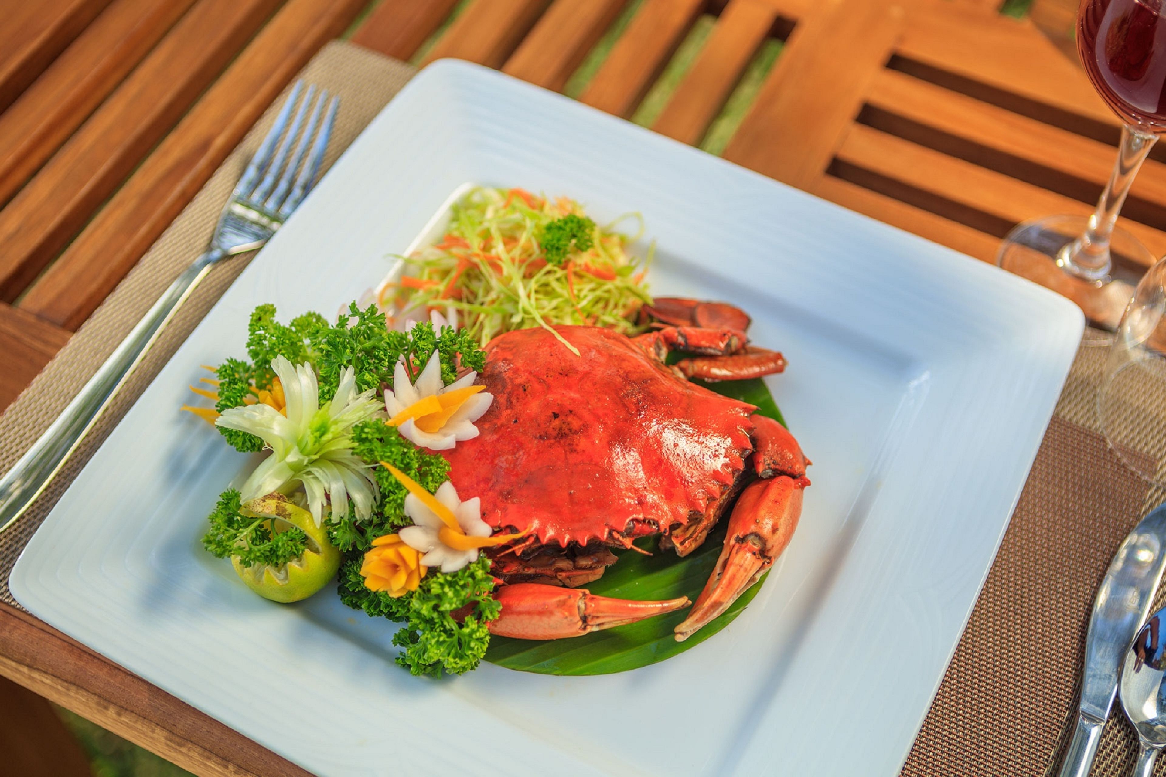 A plate of crab with vegetables and flowers on a white plate.