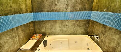 Un baño con bañera, toallero y zona de ducha con azulejos azules.