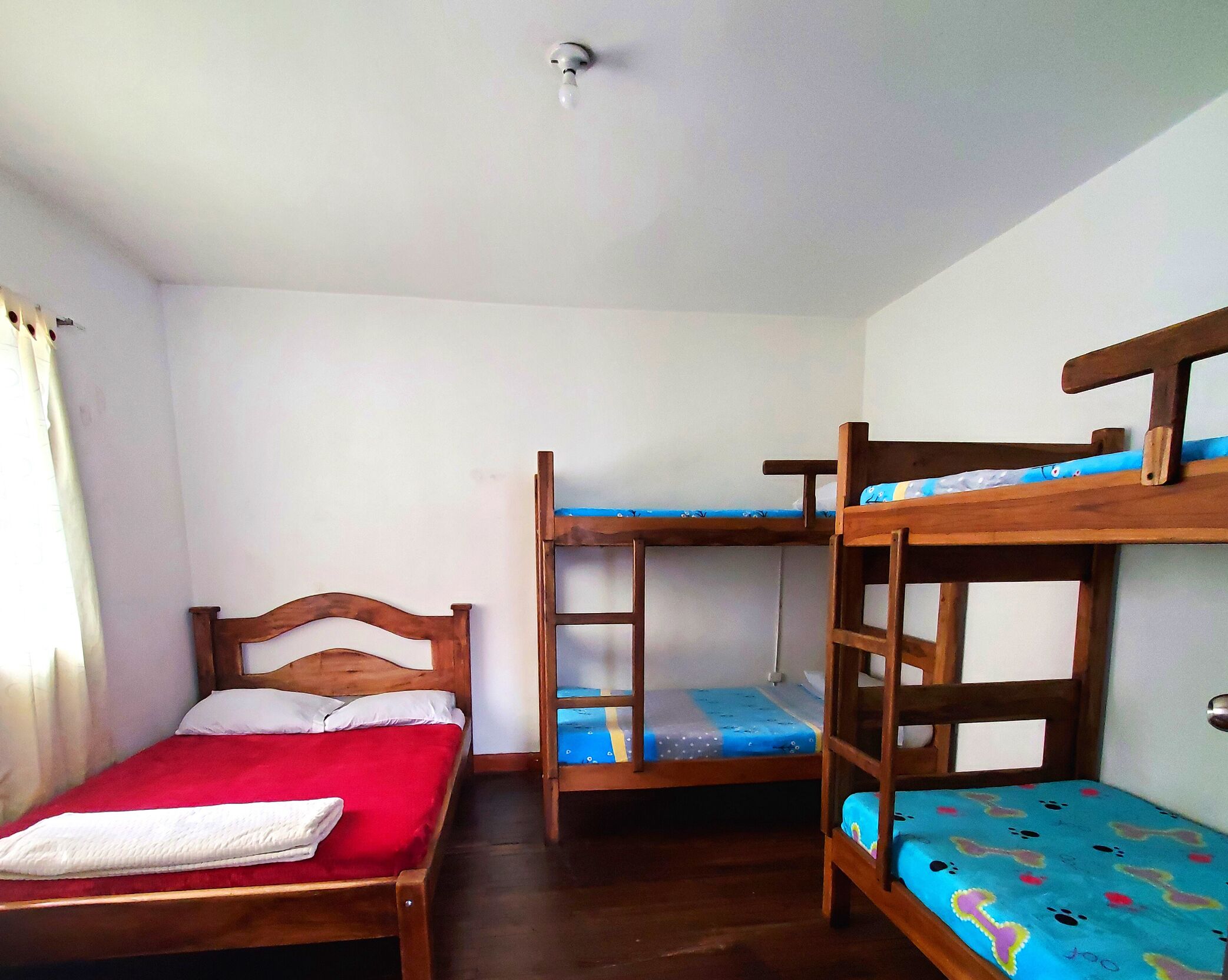 A room with three wooden bunk beds, a single bed, and a white ceiling.