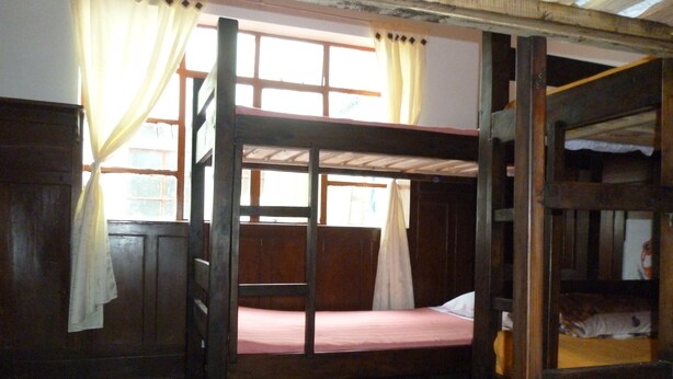 Une chambre avec un lit superposé, des murs en bois et une fenêtre avec des rideaux.