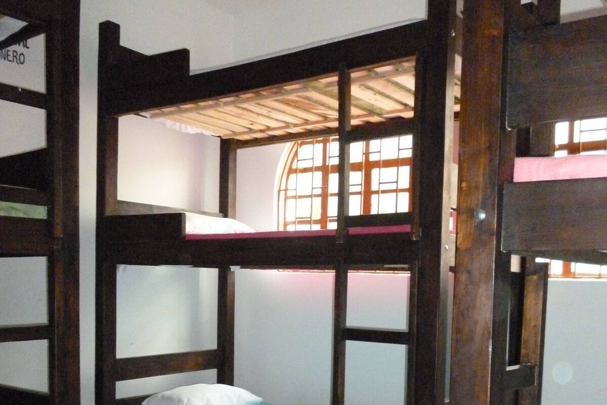 Een slaapkamer met stapelbedden, houten frames en een raam.