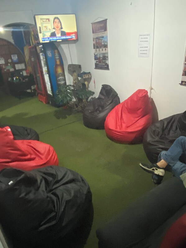 Una habitación con sillones de pie, un televisor y un cartel en la pared.