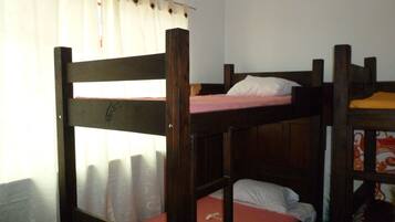 A bunk bed room with a curtain partially drawn, a wooden headboard, and a bed with a white pillow.