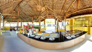 Zona de buffet con un mostrador curvo, techo de paja y vistas al exterior.