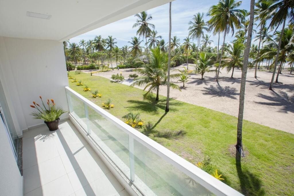 A balcony with a view of a sandy beach and palm trees.