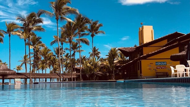 Una piscina azul cristalina con palmeras y un edificio con la palabra 'Makaia' escrita.