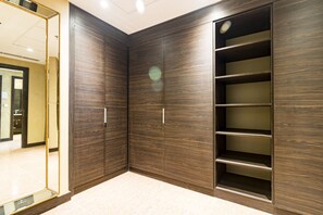 Spacious room features a wardrobe with multiple shelves and a mirrored closet door.