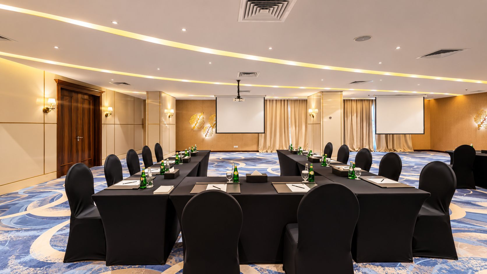 Une salle de conférence équipée d’une longue table, de chaises et d’écrans de présentation.