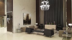 Un rebedor d'hotel modern amb una paret de marbre, una gran pèndol i una zona de seients amb sofàs i una taula de cafè.