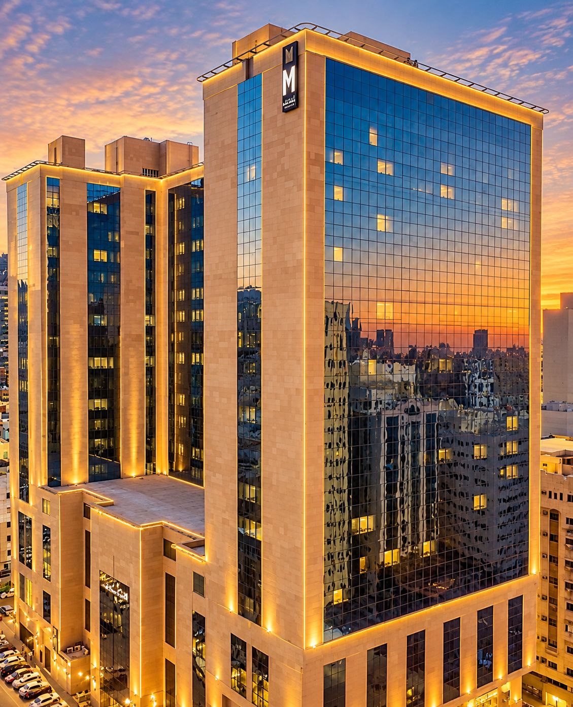 A modern hotel building with a prominent 'M' logo, multiple floors, and a reflective glass facade.