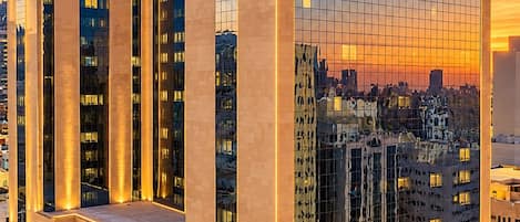 En modern hotellbyggnad med en tydlig logotyp i form av bokstaven ”M”, flera våningar och en reflekterande glasfasad.