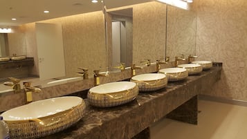 A luxury bathroom with six round, gold-patterned sinks and matching gold faucets.