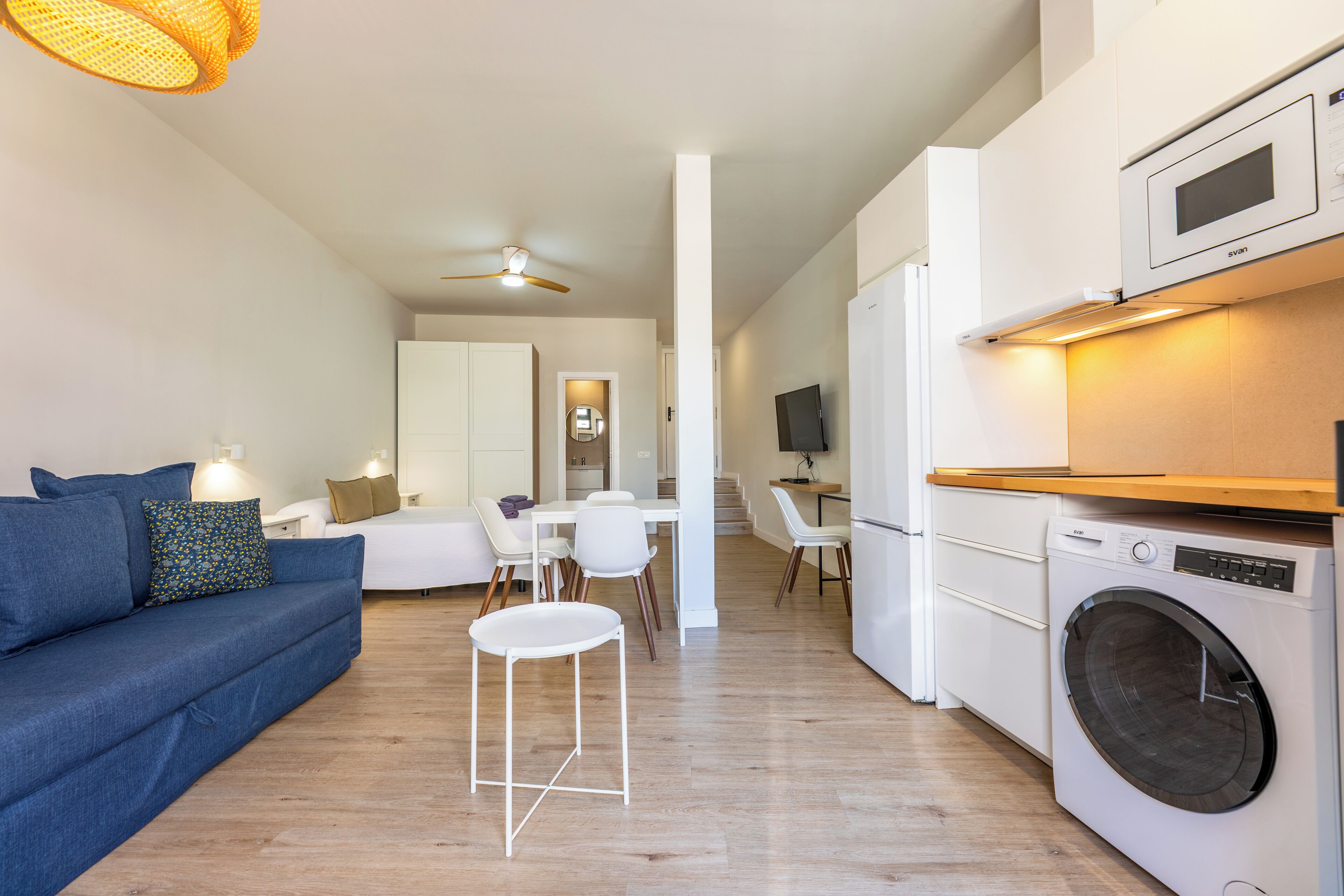 A modern apartment with a living room, dining area, kitchen, and a washing machine.