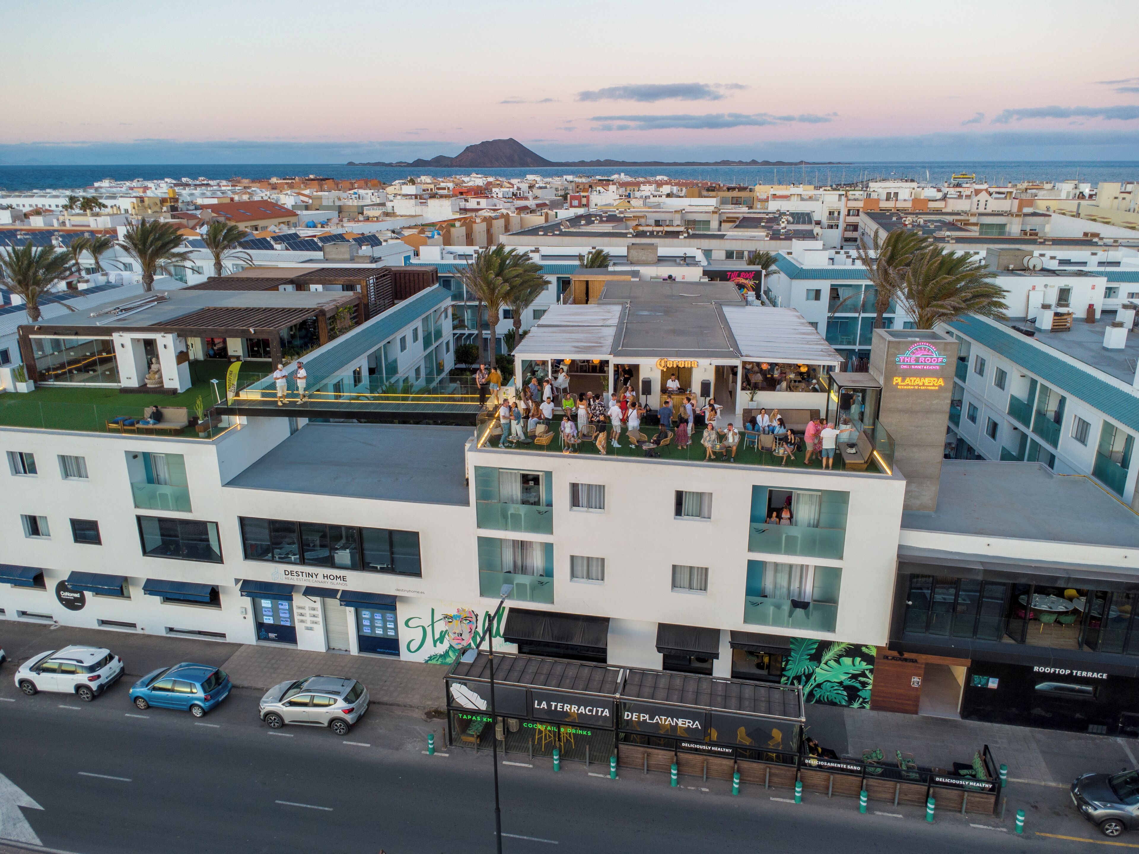 A rooftop terrace with a view of the sea, surrounded by buildings with balconies.