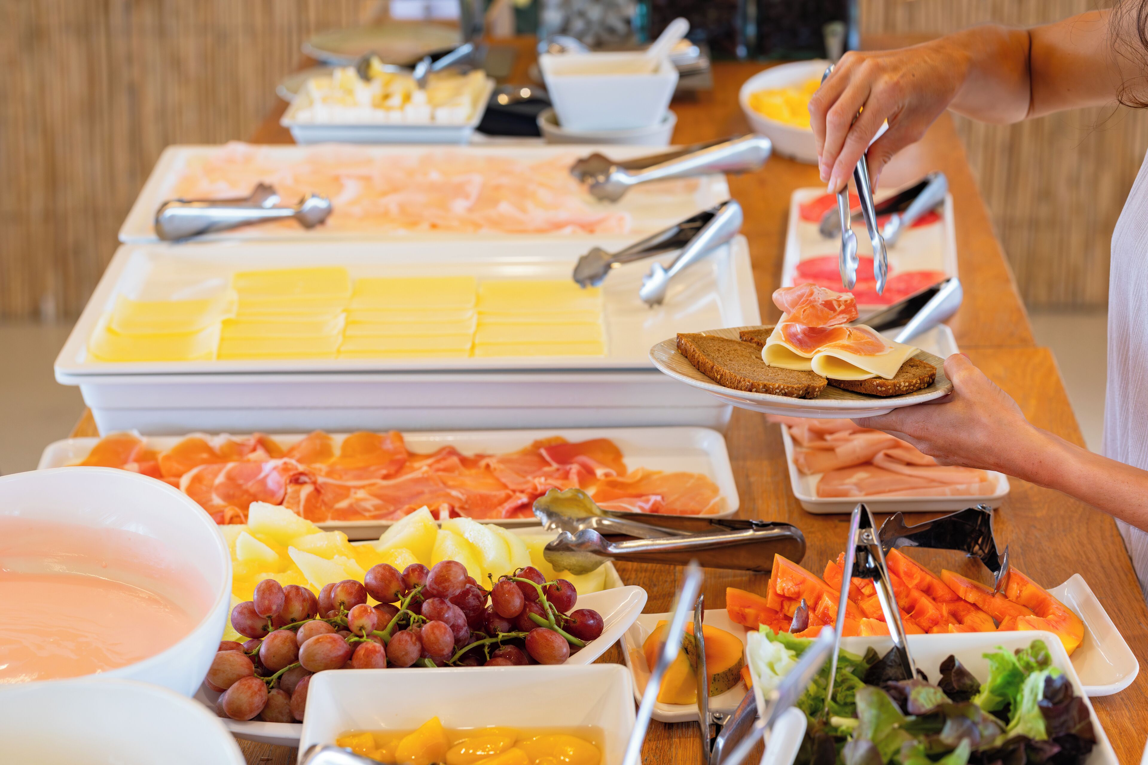 Un bufé con diversas opciones de comida, incluyendo queso, carnes, frutas y ensaladas.