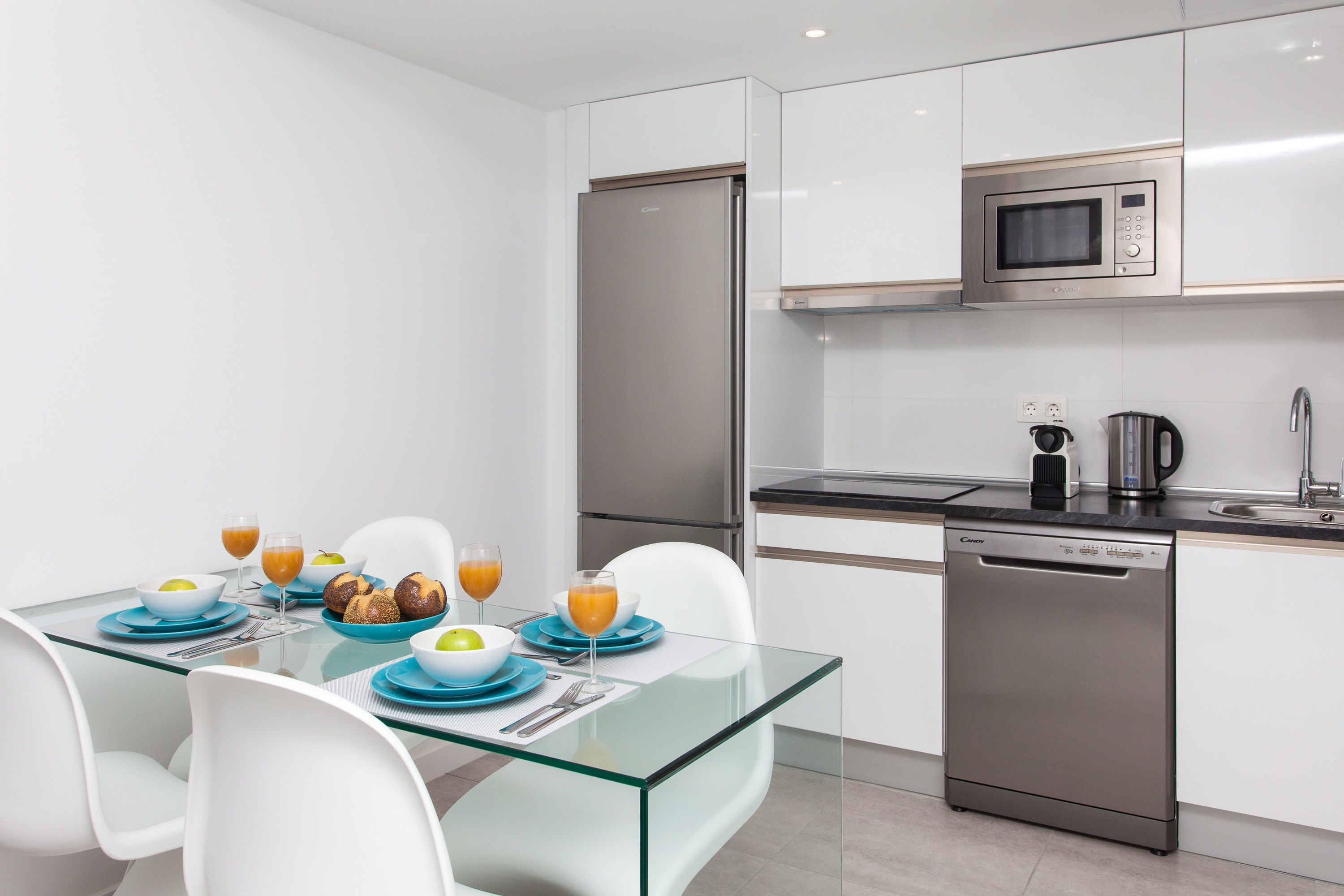 A modern kitchen with white cabinets, a stainless steel refrigerator, a microwave, and a dishwasher.